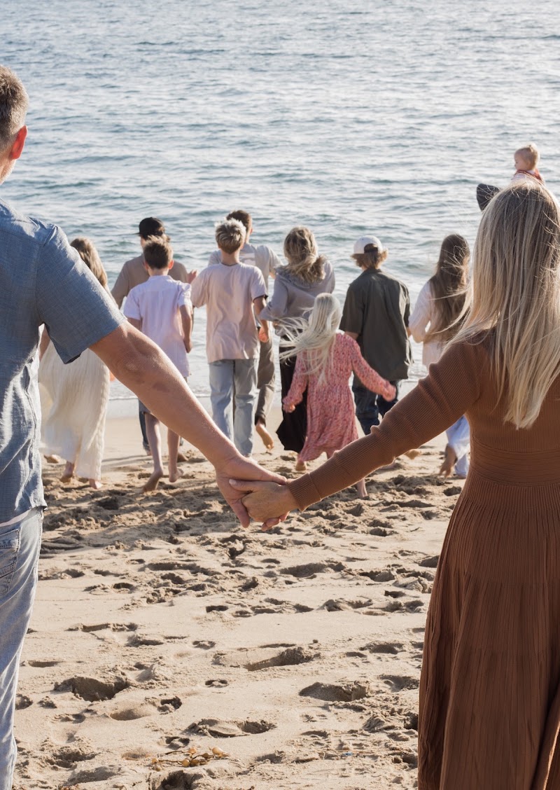 Brent and Jamie walking hand in hand with their family into the ocean